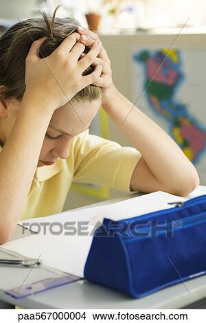 Picture - Boy sitting at desk with head in hands. Fotosearch
