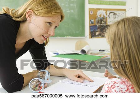 Stock Photography - Elementary teacher helping student with work. Fotosearch