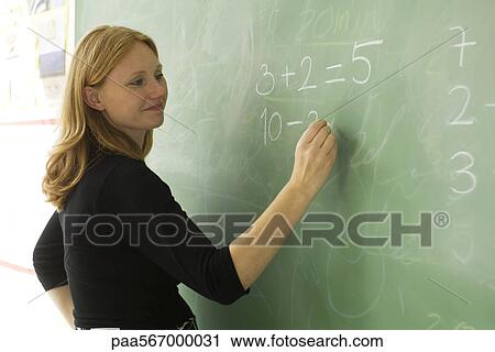 Elementary teacher writing math equations on blackboard View Large Photo Image Stock Image - Elementary teacher writing math equations on blackboard. Fotosearch