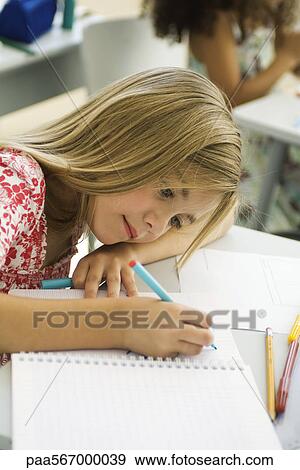 Stock Photo - Girl resting head on arm, drawing in notebook. Fotosearch