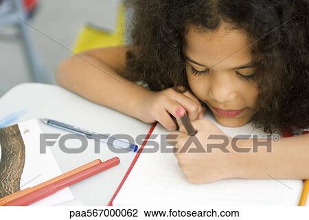 Stock Image - Little girl resting head on desk, drawing on graph paper. Fotosearch