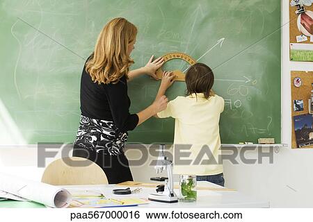 Teacher helping boy draw angle on blackboard using protractor, rear view View Large Photo Image Stock Photograph - Teacher helping boy draw angle on blackboard using protractor, rear view. Fotosearch