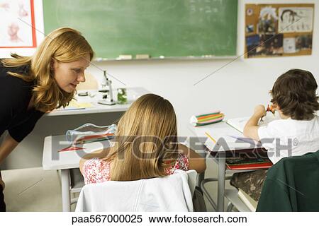 Stock Photography - Teacher helping student in elementary classroom. Fotosearch