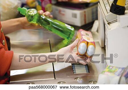 Stock Photo - Cashier scanning items at checkout counter, cropped. Fotosearch