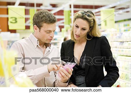Couple in store carefully reviewing product label View Large Photo Image Stock Image - Couple in store carefully reviewing product label. Fotosearch