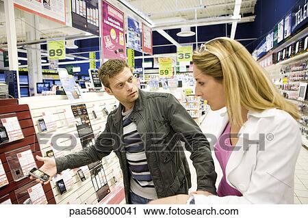 Couple looking at cell phones in electronics section of department store View Large Photo Image Stock Image - Couple looking at cell phones in electronics section of department store. Fotosearch