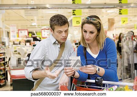 Couple reviewing sales receipt in store View Large Photo Image Stock Photo - Couple reviewing sales receipt in store. Fotosearch