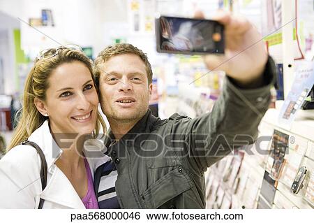 Couple taking self portrait with demo photophone in store View Large Photo Image Stock Photograph - Couple taking self portrait with demo photophone in store. Fotosearch
