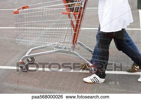 Empty shopping cart being pushed across parking lot View Large Photo Image Stock Photograph - Empty shopping cart being pushed across parking lot. Fotosearch