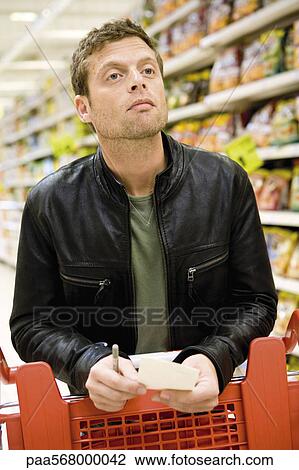 Man in supermarket with shopping list View Large Photo Image Stock Image - Man in supermarket with shopping list. Fotosearch