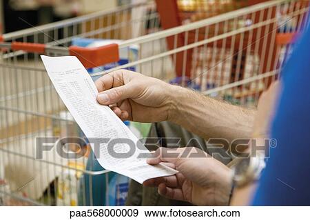 Shopper reviewing receipt, cropped View Large Photo Image Stock Photo - Shopper reviewing receipt, cropped. Fotosearch