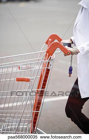 Shopping cart being pushed across parking lot View Large Photo Image Stock Photography - Shopping cart being pushed across parking lot. Fotosearch