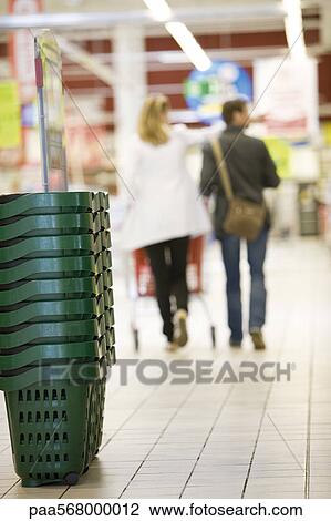 Stack of shopping baskets, shoppers in background View Large Photo Image Stock Image - Stack of shopping baskets, shoppers in background. Fotosearch