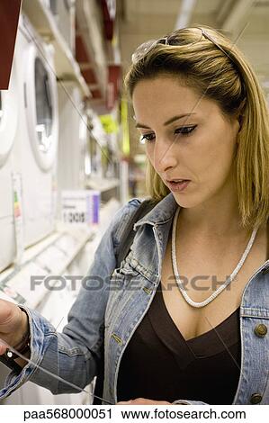 Woman looking at appliance price tag in department store View Large Photo Image Stock Image - Woman looking at appliance price tag in department store. Fotosearch