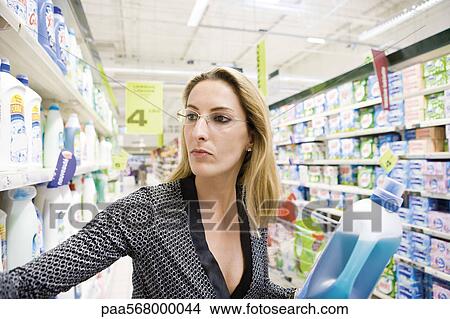 Woman selecting bottle of detergent from supermarket shelf View Large Photo Image Picture - Woman selecting bottle of detergent from supermarket shelf. Fotosearch