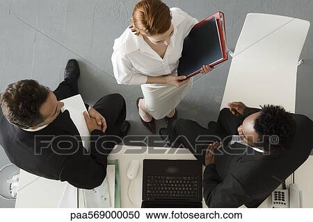 Stock Image - Business people in office having informal meeting. Fotosearch