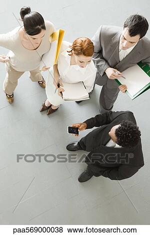 Stock Photo - Business people watching associate check cell phone. Fotosearch