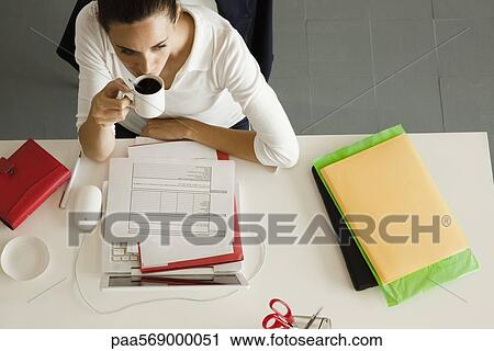 Businesswoman at desk breaking for cup of coffee View Large Photo Image Stock Image - Businesswoman at desk breaking for cup of coffee. Fotosearch