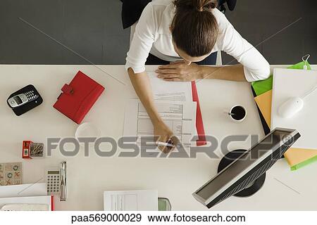 Businesswoman at desk busy with paperwork View Large Photo Image Stock Photo - Businesswoman at desk busy with paperwork. Fotosearch