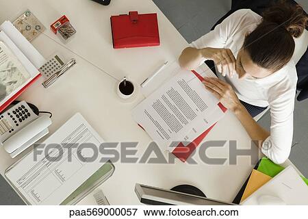 Businesswoman at desk busy with paperwork, overhead view View Large Photo Image Stock Photo - Businesswoman at desk busy with paperwork, overhead view. Fotosearch