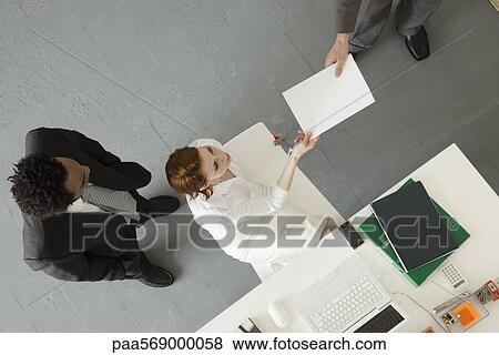 Stock Photo - Businesswoman handing document to colleague. Fotosearch