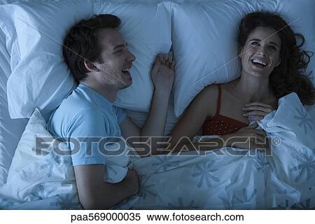 Couple lying together in bed laughing View Large Photo Image Stock Photography - Couple lying together in bed laughing. Fotosearch