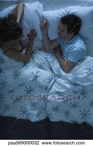 Couple lying together in bed, woman watching man sleeping View Large Photo Image Stock Image - Couple lying together in bed, woman watching man sleeping. Fotosearch