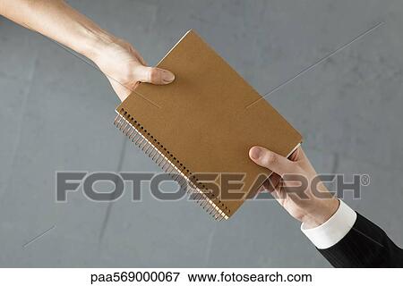 Stock Photo - Handing colleague notebook. Fotosearch
