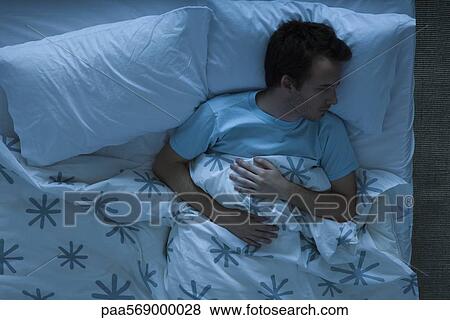 Man lying awake in bed contemplatively looking away View Large Photo Image Stock Photo - Man lying awake in bed contemplatively looking away. Fotosearch