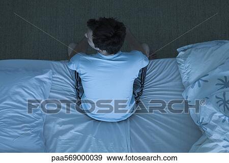 Man sitting on bed unable to sleep View Large Photo Image Stock Photo - Man sitting on bed unable to sleep. Fotosearch