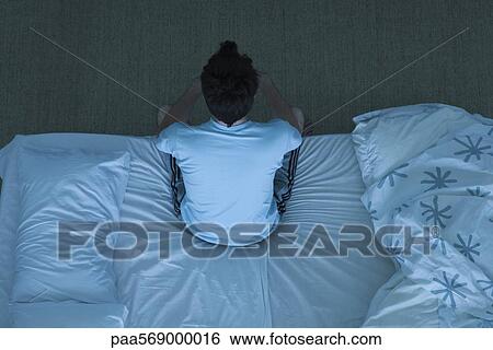 Man sitting on bed unable to sleep View Large Photo Image Stock Photograph - Man sitting on bed unable to sleep. Fotosearch