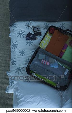 Stock Image - Packed suitcase lying open on bed. Fotosearch