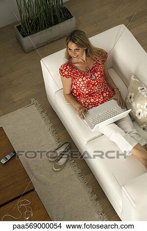 Picture - Woman relaxing at home using laptop computer. Fotosearch