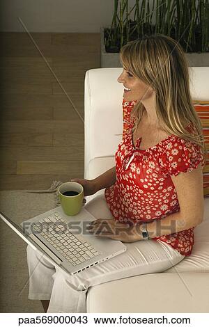 Woman relaxing at home with cup of coffee, using laptop computer View Large Photo Image Stock Image - Woman relaxing at home with cup of coffee, using laptop computer. Fotosearch