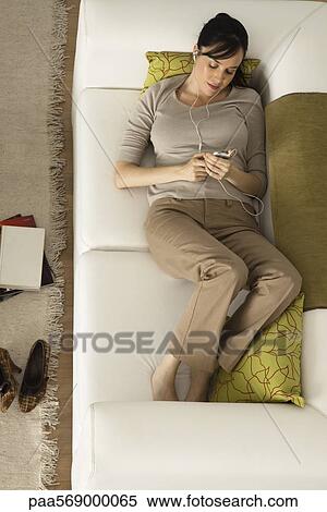 Woman relaxing on sofa listening toMP3 player View Large Photo Image Stock Photography - Woman relaxing on sofa listening toMP3 player. Fotosearch