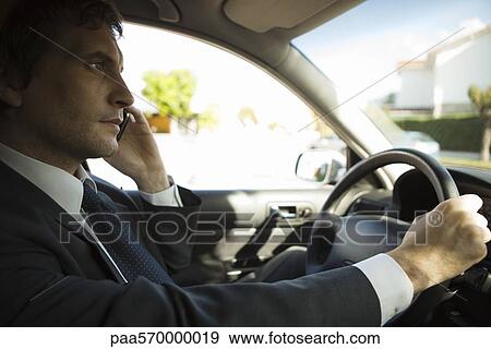 Businessman using cell phone while driving View Large Photo Image Stock Photo - Businessman using cell phone while driving. Fotosearch