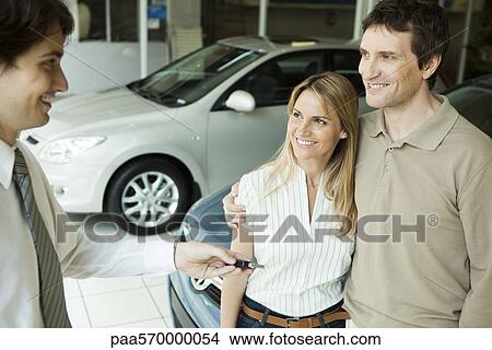Car salesman handing key to couple View Large Photo Image Picture - Car salesman handing key to couple. Fotosearch