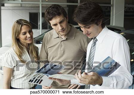 Car salesman showing couple brochure View Large Photo Image Stock Image - Car salesman showing couple brochure. Fotosearch