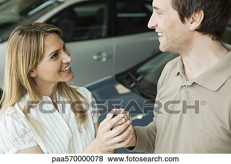 Couple in car dealership showroom with key to new car View Large Photo Image Stock Photo - Couple in car dealership showroom with key to new car. Fotosearch