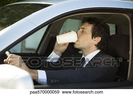 Man drinking coffee while driving car View Large Photo Image Stock Photo - Man drinking coffee while driving car. Fotosearch