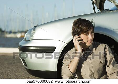 Stock Image - Man having car trouble, making phone call with cell phone. Fotosearch