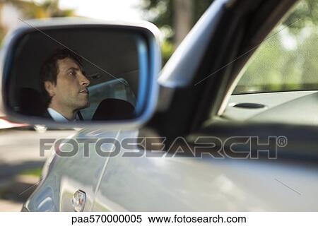 Stock Photography - Reflection of car driver seen in side-view mirror. Fotosearch