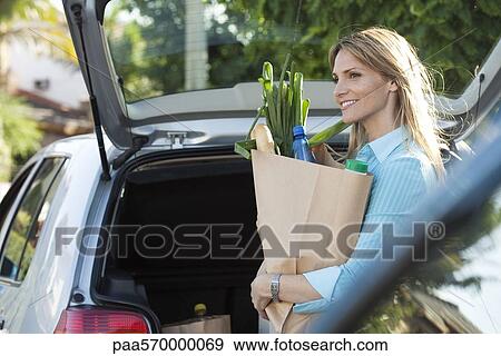 Woman putting groceries in back of hatchback View Large Photo Image Stock Photo - Woman putting groceries in back of hatchback. Fotosearch