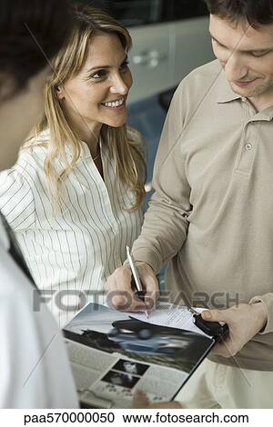 Woman watching husband as he signs document and accepts keys to new car View Large Photo Image Stock Image - Woman watching husband as he signs document and accepts keys to new car. Fotosearch
