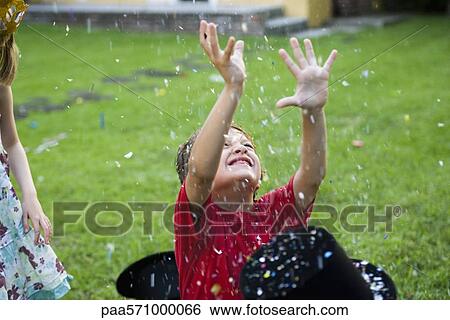 Boy with arms raised showered in falling confetti View Large Photo Image Stock Photograph - Boy with arms raised showered in falling confetti. Fotosearch