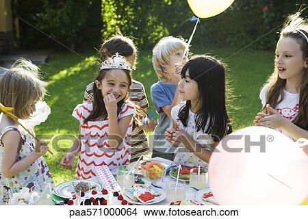 Picture - Children eating sweets at birthday party. Fotosearch