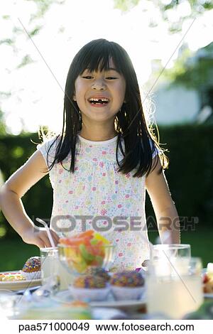 Girl at party admiring sweets placed on table View Large Photo Image Stock Photo - Girl at party admiring sweets placed on table. Fotosearch