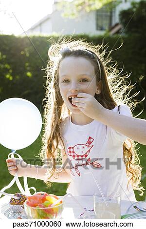 Girl holding balloon and eating candy View Large Photo Image Stock Image - Girl holding balloon and eating candy. Fotosearch