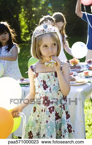 Girl wearing tiara and blowing party horn blower at outdoor party View Large Photo Image Stock Image - Girl wearing tiara and blowing party horn blower at outdoor party. Fotosearch