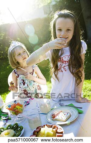 Stock Photo - Girls eating sweets at birthday party. Fotosearch
